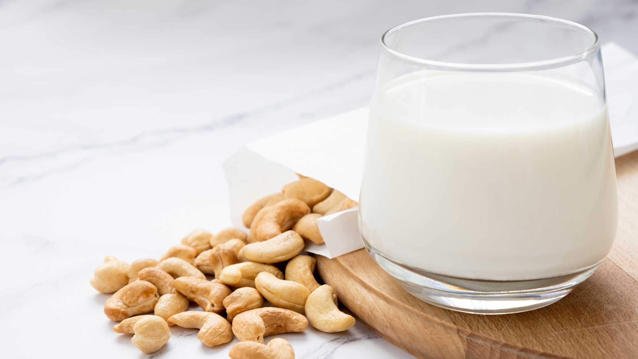 Plant-based-milk-with-heap-of-cashew-nuts-on-wooden-board